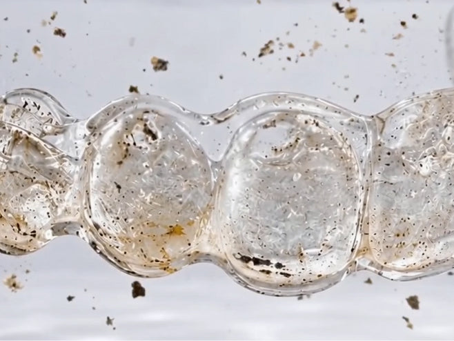 Ultrasonic bubbles lifting debris from a transparent dental aligner